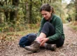 A person holding a swollen, twisted ankle after rolling it on an uneven path.